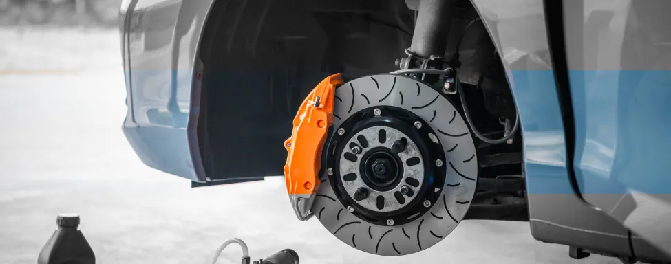 Brake Repair In Sterling, VA At Honest Tom Care. A close-up of a car's brake disc and caliper with a tire removed, showing the brake assembly.