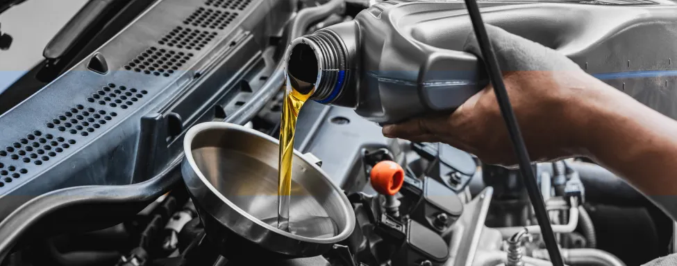 Oil Change Service In Sterling, VA At Honest Tom Care. A hand pouring new motor oil from a bottle into a car's engine.