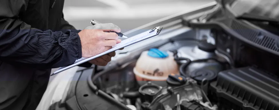 Vehicle Inspections In Sterling, VA At Honest Tom Care. A mechanic using a flashlight to perform a vehicle inspection on a car lifted up in a garage.
