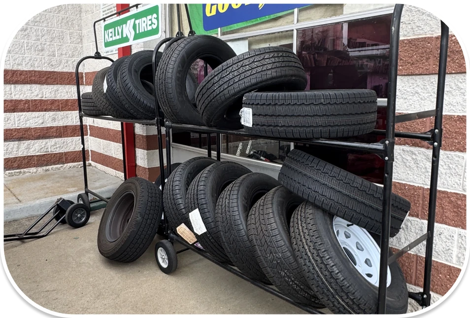 A metal rack full of new black tires is parked outside on an asphalt surface.