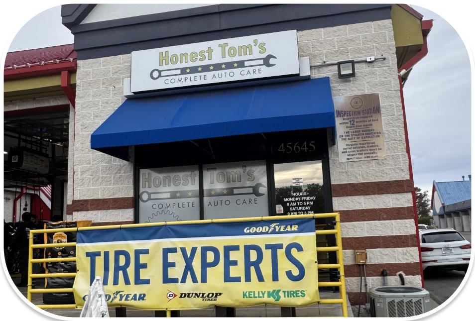 The exterior of an auto repair shop with a blue awning and a large yellow banner that says Tire Experts.